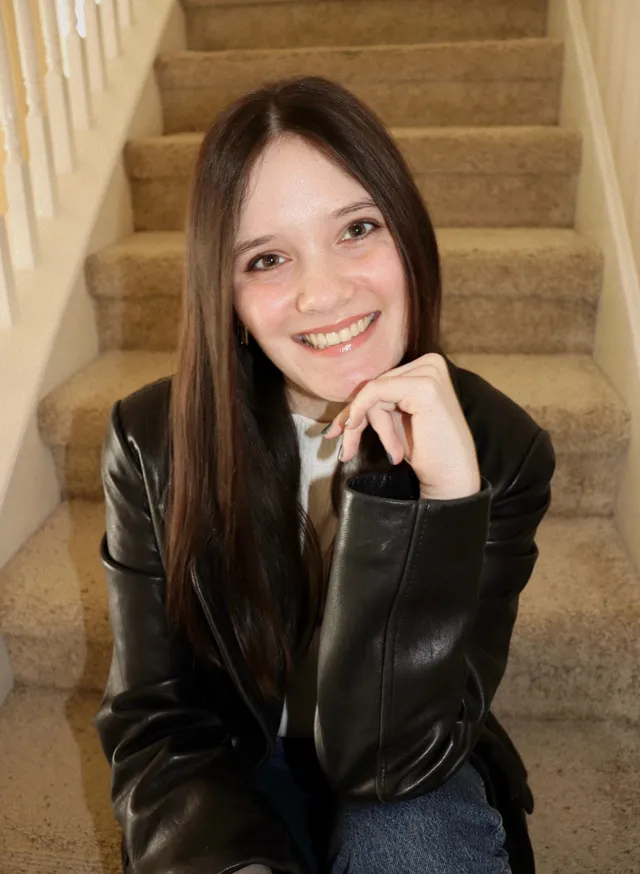 Kayley Cannon smiling, sitting on a staircase