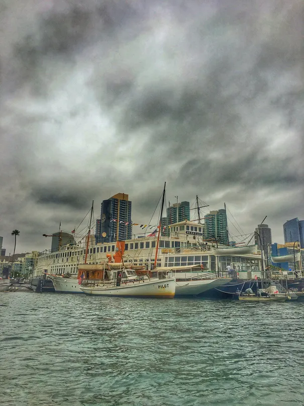 Riverboat docked beneath a stormy city skyline