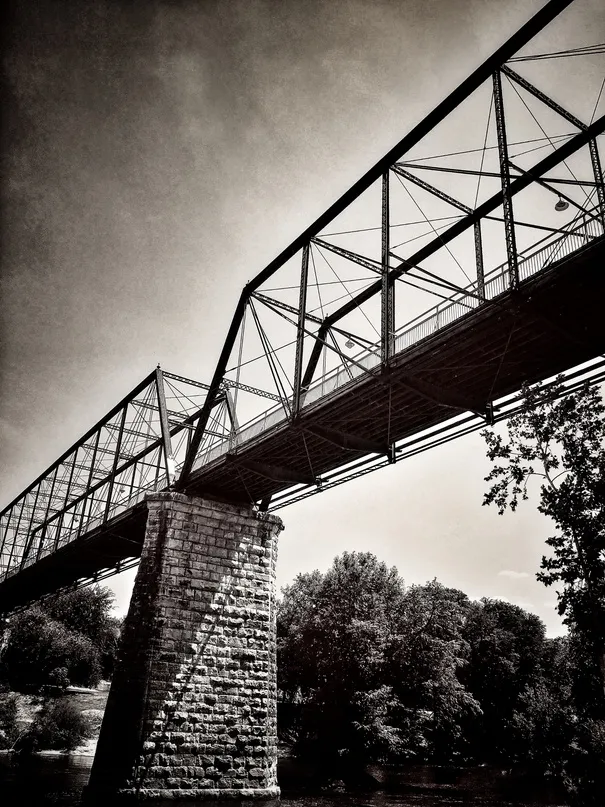 Steel truss bridge over a river, in black and white