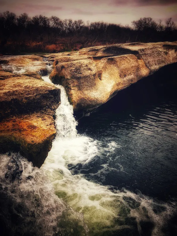 Waterfall rushing over rocks at dusk
